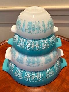 three blue and white dishes stacked on top of each other in front of a wooden table