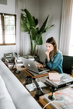 a woman sitting at a desk with a laptop computer in front of her and books on the table