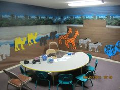 a table and chairs in front of a wall with animals painted on the walls behind it