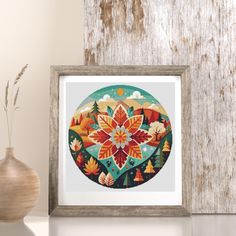 a cross stitch pattern in a frame next to a vase