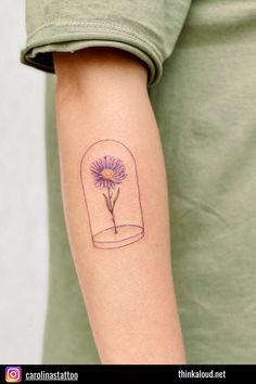 a person with a tattoo on their arm holding a purple flower in a glass jar