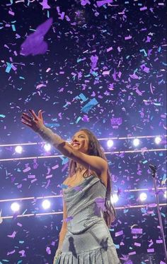 a woman standing on top of a stage with confetti falling from the air