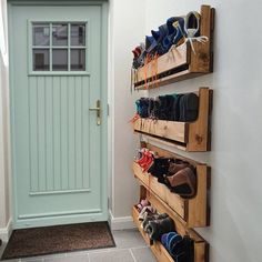 there are many pairs of shoes on the shelves next to the door in this hallway