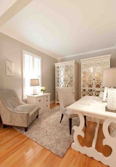 a living room filled with furniture and a white table in front of a chair on top of a hard wood floor