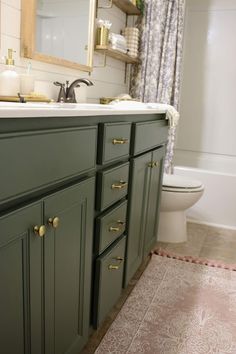 a bathroom with green cabinets and a white toilet