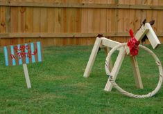 a wooden horse with a red ribbon tied around it's neck standing in the grass