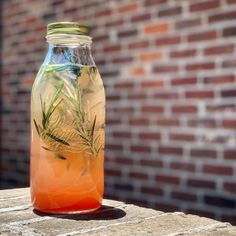 a glass jar filled with liquid sitting on top of a table next to a brick wall