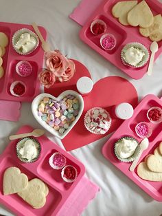 valentine's day desserts are arranged on pink trays with heart shaped cupcakes