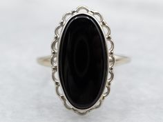 "Timeless and elegant, this ring features a low profile and sweeping lines. Crafted of scalloped white gold, this vintage ring has a smooth center, easy to wear, and comfortable on the hand. The deep black onyx gem has a perfect polish and is well-proportioned to the golden frame. Metal: 10K White Gold Gem: Black Onyx Gem Measurements: 8.1 x 16.4 mm, Oval Ring Size: 5.50 Marks: \"10K - PSC\" Stamped on the inside band  SKU #: A36205 Each piece has been identified and graded by a Graduate Gemologist who has been certified by the Gemological Institute of America (GIA). We have six brick-and-mortar storefronts in Maine, Massachusetts and New Hampshire and have been in business for over 25 years! Please visit our Shop's About Page or our website for more information about our jewelry. For ques Ring Board, Right Hand Ring, Golden Frame, Right Hand Rings, Hand Ring, Oval Ring, Black Onyx Ring, Cabochon Ring, Oval Rings