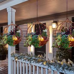 three hanging planters filled with plants on a porch next to a white picket fence