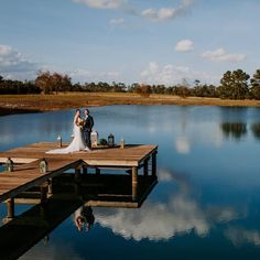 a bride and groom standing on a dock by the water