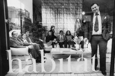 a group of people sitting around a table in front of a man with a mask on