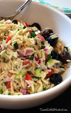 a white bowl filled with pasta salad and olives