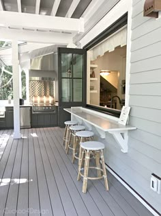 an outdoor kitchen with stools on the front porch