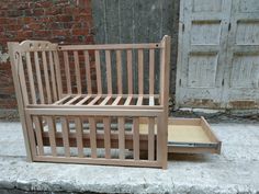 a wooden bed frame sitting on top of a sidewalk next to a brick wall and door