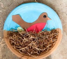 a paper plate with a bird in the nest on it's side, painted blue and brown