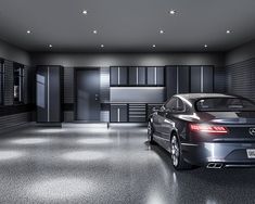 a car is parked in a garage with black cabinets and lights on the wall behind it