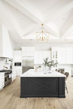 a large kitchen with white cabinets and black island