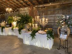 a table is set up with white linens and greenery for a wedding reception