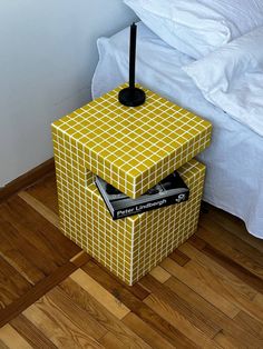 a yellow and white box sitting on top of a wooden floor next to a bed