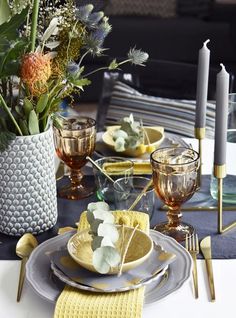 the table is set with plates, silverware and flowers in vases on it