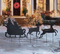 a metal sleigh with reindeers on it in front of a house