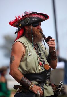 a man with a pipe in his mouth wearing a hat and feathered headdress