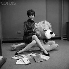 a woman sitting on the floor next to a stuffed animal