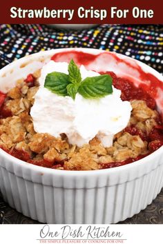 strawberry crisp for one in a white bowl with whipped cream and mint garnish