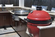 a big red grill sitting on top of a kitchen counter next to a sink and oven