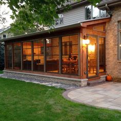 a house that is sitting in the grass with some lights on it's windows