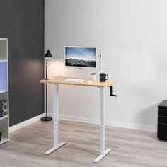 a desk with a computer monitor on top of it and a lamp next to it