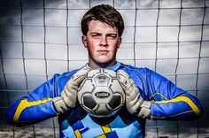 a young man holding a soccer ball in front of a goalie's net