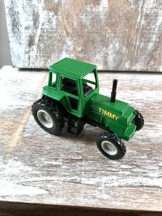 a green toy tractor sitting on top of a wooden table