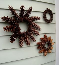 three different types of pine cones hanging on the side of a white house with two wreaths