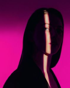 a woman's face and neck are shown in the shadows on a pink background