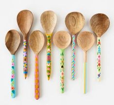 six wooden spoons lined up in a row with floral designs on them, all painted different colors