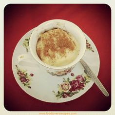 a bowl of food on a plate with a spoon next to it and a red table cloth