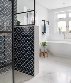 a white bathroom with black and white tiles on the shower wall, tub and sink