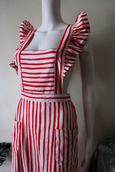 Pretty Vintage Fenno-Sport apron dress from the 1970s. Comfortable cotton blend fabric with irregular red stripes on white background. Midi length, elasticated waist. Large ruffles along the shoulder straps. The straps are crossed over in the back and attached to the waistband with buttons (length adjustable). Two patch pockets on the front. Wide skirt with ruffle hem. Unlined.  Made in Finland! Perfect for a summer vacation! Looks great with a white top or t-shirt underneath and a pair of sanda Skirt With Ruffle Hem, Wide Skirt, Patch Dress, Vacation Looks, Apron Dress, Red And White Stripes, Red Fabric, Dress Clothes For Women, White Top