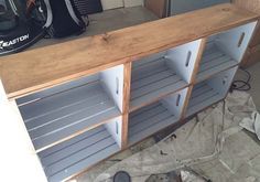 a wooden cabinet with metal shelves in front of it and a helmet on the floor next to it