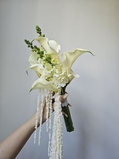 a hand holding a bouquet of flowers with pearls hanging from it's stems,