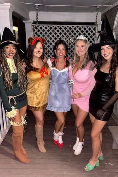 four women dressed up in costumes posing for a photo on the porch at a halloween party