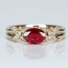 a close up of a ring with a red stone in the middle and white diamonds around it