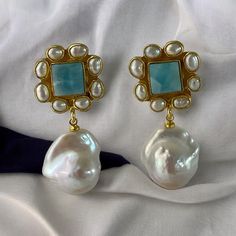 **Handmade Gemstone and Baroque Earrings** Introducing our stunning handmade gemstone and Baroque earrings, now available in two exquisite new gemstones: Larimar and Lapis Lazuli. This best-selling design features genuine stones surrounded by delicate rice pearls, bezel-rimmed in luxurious 22k gold plating.  **Featured Gemstone: Larimar** The centerpiece of these earrings is a genuine Larimar stone, known for its smooth and beautiful blue hues. Each stone measures approximately 18x18mm, creating Baroque Pearls Earrings, Larimar Earrings, Baroque Pearl Earrings, Baroque Pearls, Jewelry Pouch, Unique Earrings, Wedding Earrings, Lapis Lazuli, Handmade Earrings