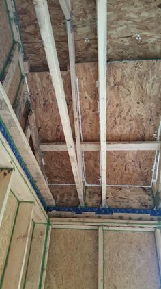 the inside of an unfinished room with wood framing and insulation tape on the ceiling,