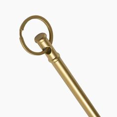 a gold colored metal object with a circular handle on it's end, against a white background