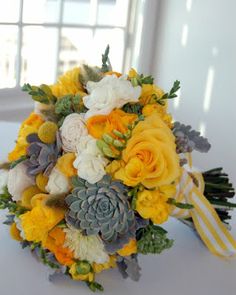 a bridal bouquet with succulents and yellow flowers on a white table