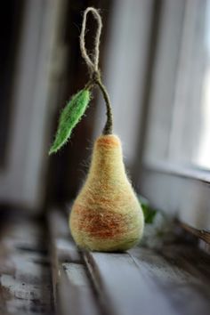 a needled pear hanging from a string with a green leaf on it's tip