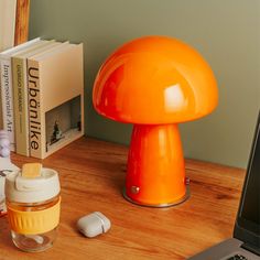 an orange mushroom lamp sitting on top of a wooden desk next to a laptop computer